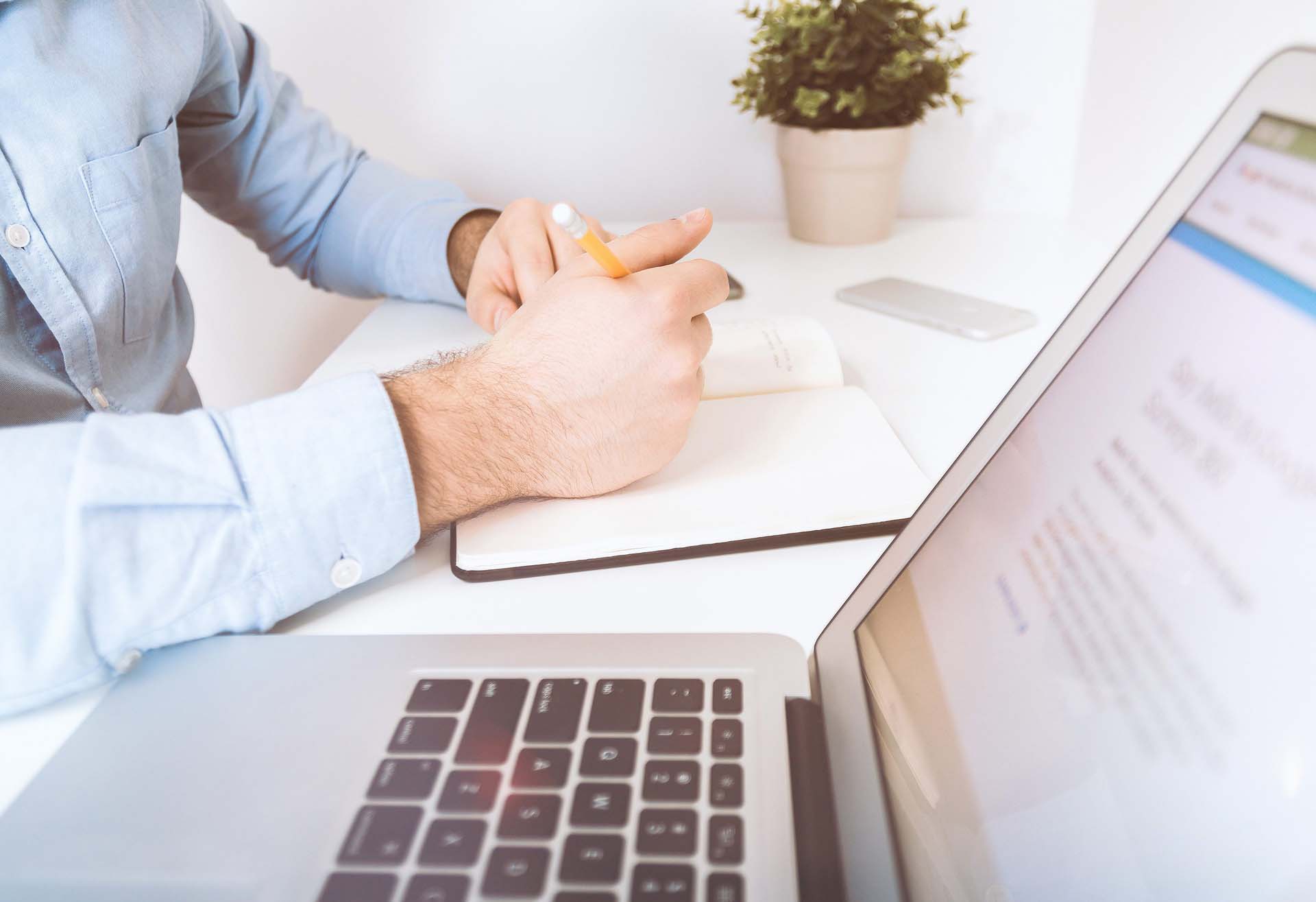 Man writing Digital Marketing Insights next to an open laptop