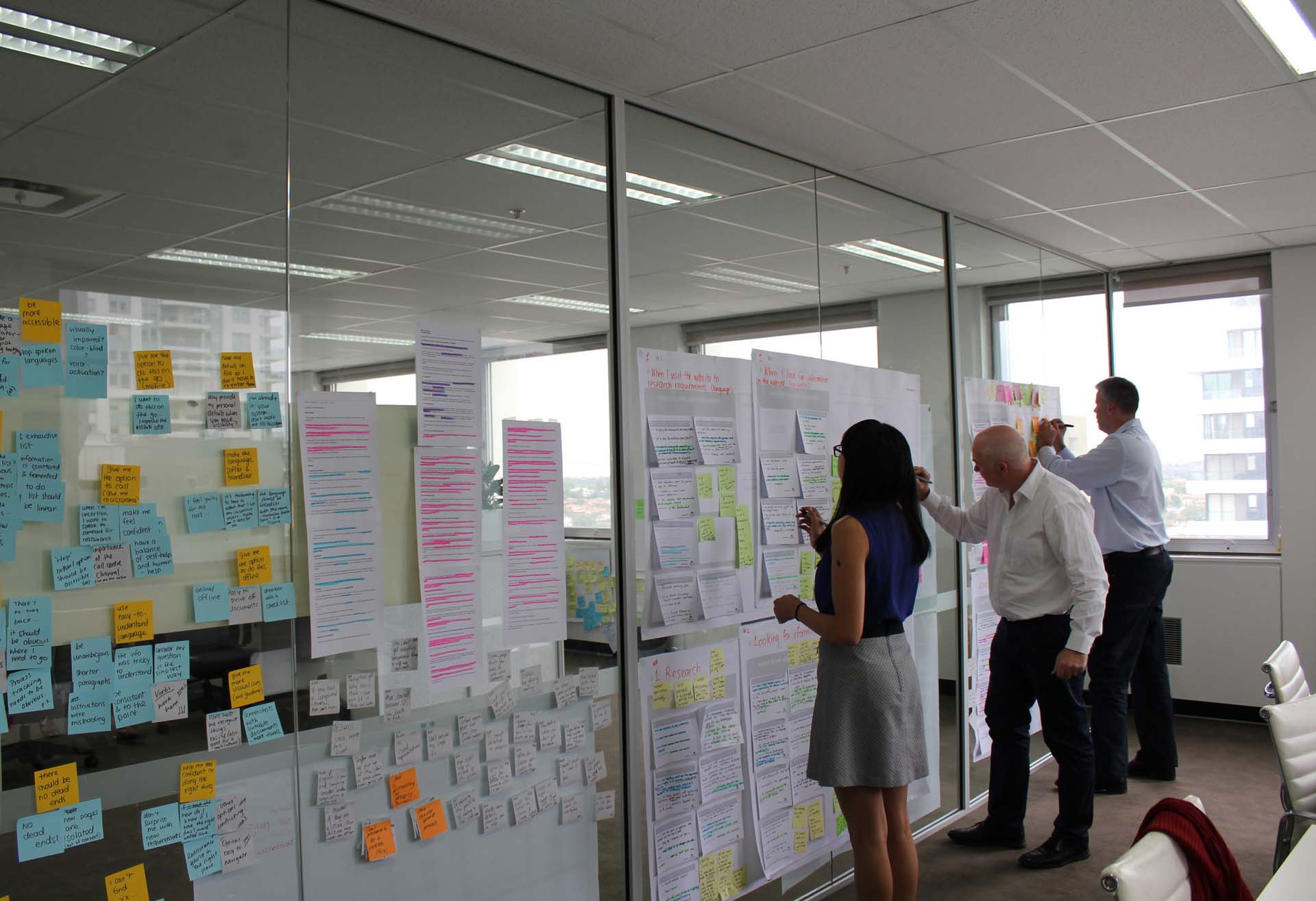 Three Proto employees making notes on a large Customer Journey Map