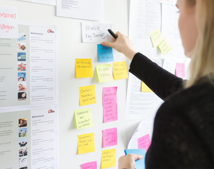 Woman putting notes on a customer insights wall